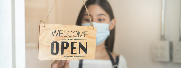 Owner of cafe wear protective face mask flipping sign to close