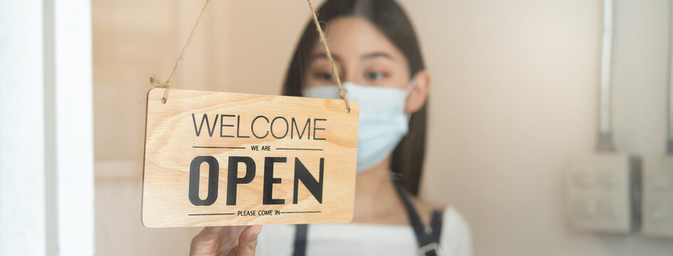 Owner Of Cafe Wear Protective Face Mask Flipping Sign To Close