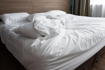 Soft pillows on comfortable bed.Empty bedroom, pillow, blanket and white linen after wake up.The crease of an unmade bed sheet in the bedroom after night sleep and wake up in the morning time.