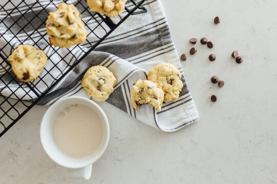 chocolate chip cookies and milk in a white mug on the counter with a gray striped napkin