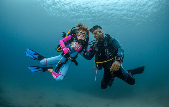 child scuba diver and adult diver go diving