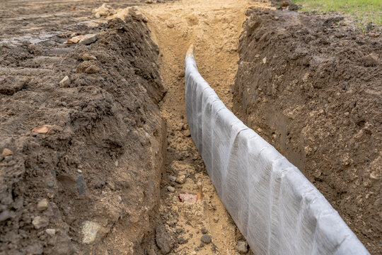 Construction photo of natural turf athletic field vertical edge drain profile, drainage panel between baseball / softball infield clay and natural grass field.