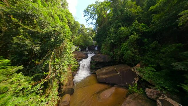 Scenic FPV flight over tropical river and waterfalls among ush jungle in Thailand