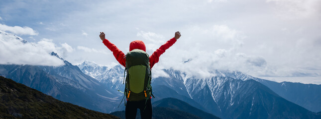 Woman hiker enjoy the view on mountain top cliff edge face the snow capped mountains in tibet