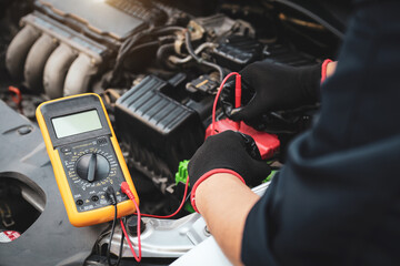 Hand car mechanic with voltmeter to check voltage car battery energy problem for service...