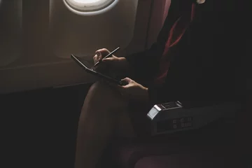 Rideaux occultants Avion Blonde female tourist checking incoming notification on smartphone sitting on seat of airplane with netbook.Young businesswoman share media from telephone on laptop computer during plane flight