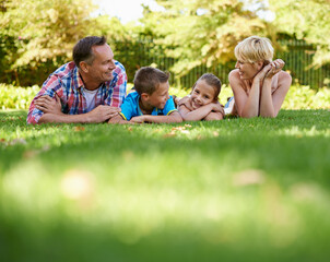 Garden, park and happy family relax on grass in summer or parents and children together. Mother, father and kids smile in backyard on holiday or vacation in forest, woods or enjoy sunshine in nature
