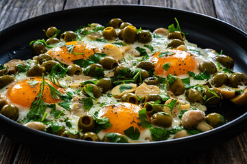 Shakshuka - fried eggs with vegetables on wooden table
