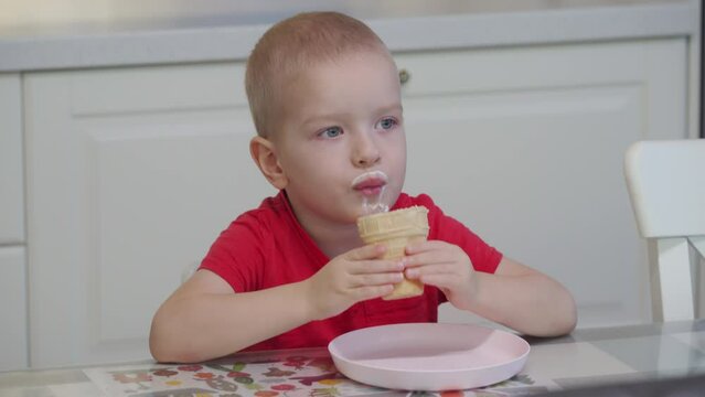 3-year-old child licking ice cream in a waffle cup at home