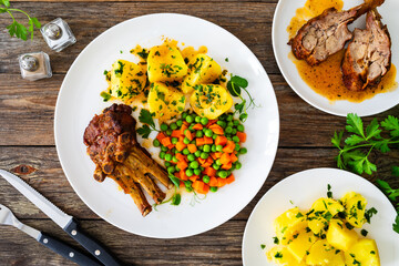 Veal ribs, boiled potatoes, peas and carrots on wooden table
- 759468893