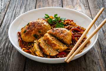 Asian style stir fried vegetables, pork meatballs and chow mein noodles on wooden table
