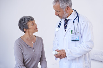 Fototapeta premium Hospital, consulting and doctor with pills for patient for prescription, medicine and treatment. Healthcare, medication and senior woman in consultation for medical service, wellness and diagnosis