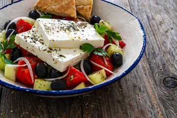 Greek style salad - fresh vegetables with feta cheese nad pita bread on wooden table
