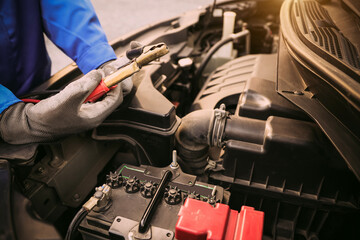 Close-up hand auto mechanic using connect jumper cable on terminal dead battery for jump-start or...