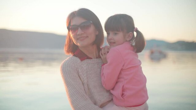 Mothers with daughter by the sea at sunset