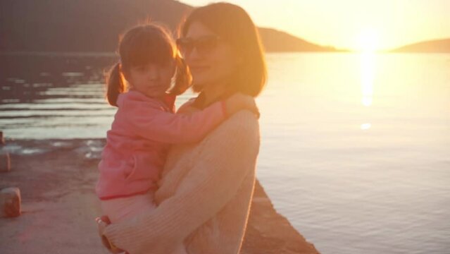 Mothers with daughter by the sea at sunset