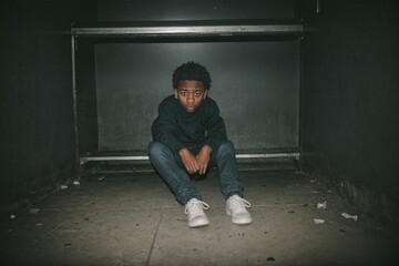 A scared and battered man sitting alone in a dark and oppressive cell, reflecting the despair of domestic violence