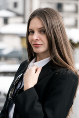 A stylish woman in a black suit and white shirt with glasses poses for the camera against the backdrop of snowy mountains. Fashion shooting concept. Vertical video