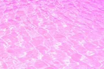 Pink water background with ripples, splashes and bubbles. Clear water surface texture or natural ripple background with reflection sunlight