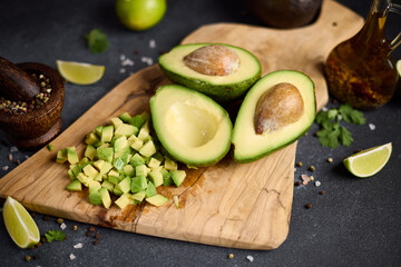 Halved green avocado fruit on wooden cutting board at domestic kitchen