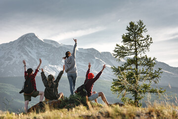 Group of happy young hikers are having fun in sunset mountains