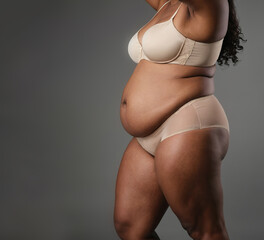 An african american woman with a large belly is wearing a bra and panties. Concept of confidence and self-acceptance, as the woman is not ashamed of her body and is comfortable showing it off