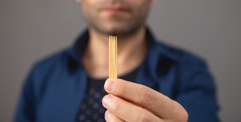 Caucasian man with a wooden toothpick.