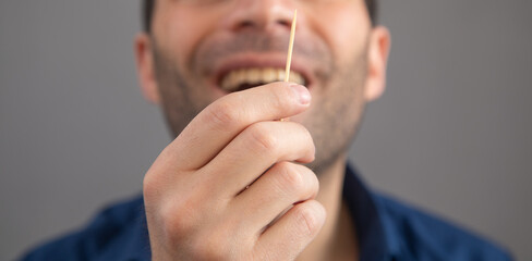 Caucasian man with a wooden toothpick.