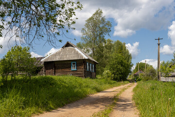 Summer rural landscape. View of the village street and huts. Everyday life in the village. Old traditional wooden houses. Village Zaborovye, Novgorod region, Russia.