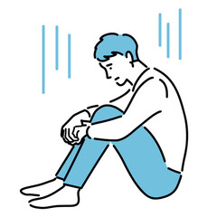 しゃがみこんで落ち込んでいる若い男性

