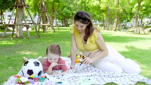 Mother and Child Playing on Picnic Blanket, A mother spend free time holiday outdoors with son surrounded by greenery, woman and a toddler drawing a book together, family relationship carefree weekend