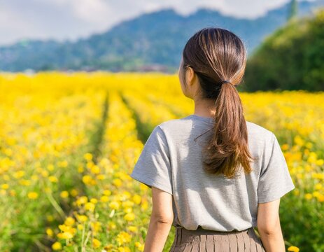Woman walking in a yellow flower field
