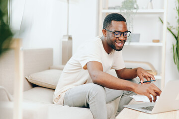 Smiling African American Freelancer Working on Laptop in Modern Home Office Millennial man sitting...