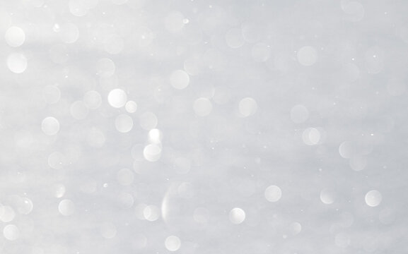 Blurred white bokeh background, snow sparkles in the sun