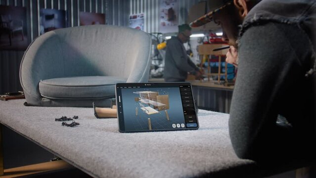 Designer creates 3D model of wooden bedside table using digital tablet and stylus. Creative man works in professional ai software for furniture design creation and 3D modeling. Design innovation