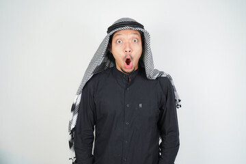 Wow face shocked expression Asian Muslim man wearing Arab turban sorban pointing hand finger at empty space
