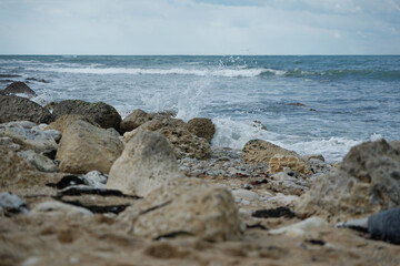 Fototapeta na wymiar Vagues qui éclaboussent sur des rochers en bord de mer. 