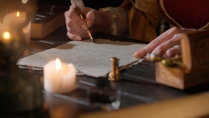 Female in antique outfit writes with feather pen. Focus on woman in renaissance dress writing a...