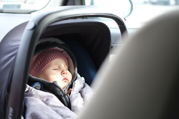 baby girl in the car, warmly dressed, travel - obrazy, fototapety, plakaty