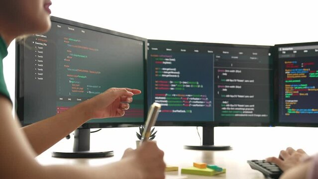 Slow motion back end software developer engineer for computer programming working together on debugging writing computing code, solving complex algorithms display on monitor in office. Burgeoning