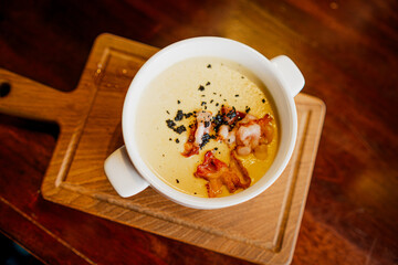 A bowl of soup is placed on a wooden cutting board, showcasing a simple yet comforting meal.
