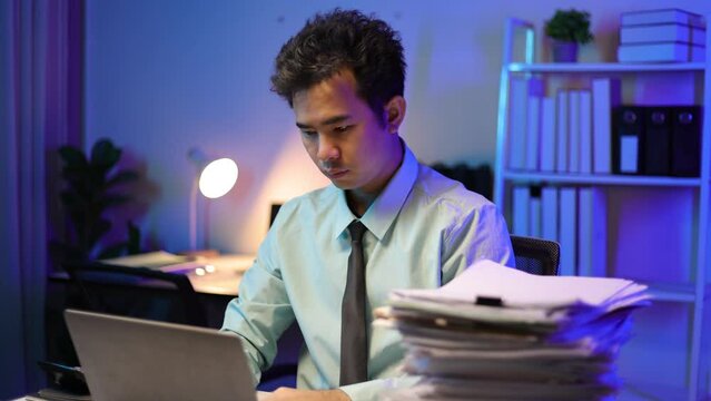 Businessman working overtime in the office. Man with a pile of documents on his desk.