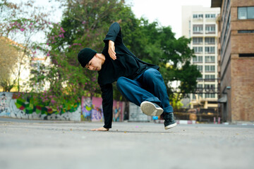 Hip hop dancer in fashionable clothes dancing on the city street © Prathankarnpap
