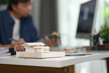 A model of houses on desk in an office with architect man sitting in background