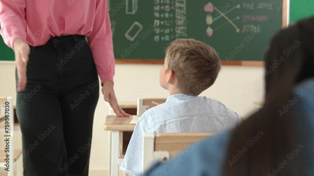 Poster energetic smart teacher explain classwork to caucasian boy at classroom while multicultural student 