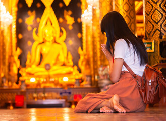 Woman traveller pray respect to the buddha statue in the temple, Thai and Asia traditional