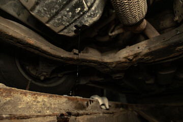 A black stream of motor oil flows from the car engine into a canister during replacement. Changing old car oil in the garage during car maintenance.