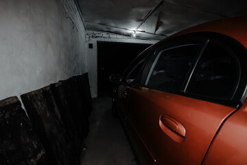 The car is parked in the garage of a house at night with the gate open Side view of a car parked in a home garage with the gate open to the street The car in the garage is protected from the weather.