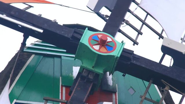 Plano cerrado del anillo giratorio adornado con pintura de diversos colores que soporta las aspas girando de un molino de viento holand&eacute;s centenario en Zaanza Schans, Holanda.