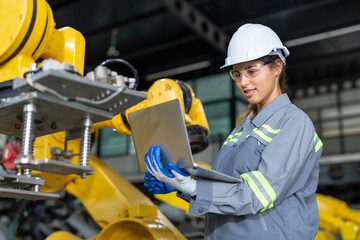 Engineer woman using laptop checking robot arms machine at assembly robotic factory. Female...